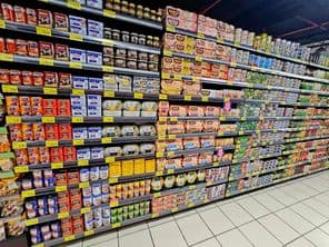 polica v supermarkete s farebnými konzervami, tuniakom a zeleninou