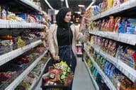 Mladá arabská žena sa pozerá na svačiny v supermarkete.