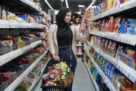 Mladá arabská žena sa pozerá na svačiny v supermarkete.