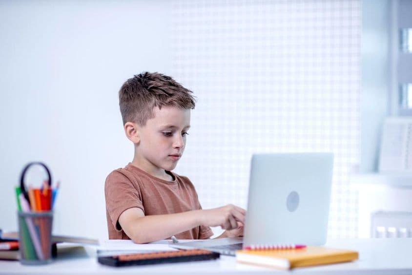 Školák hovorí s učiteľom cez videokonferenciu na počítači