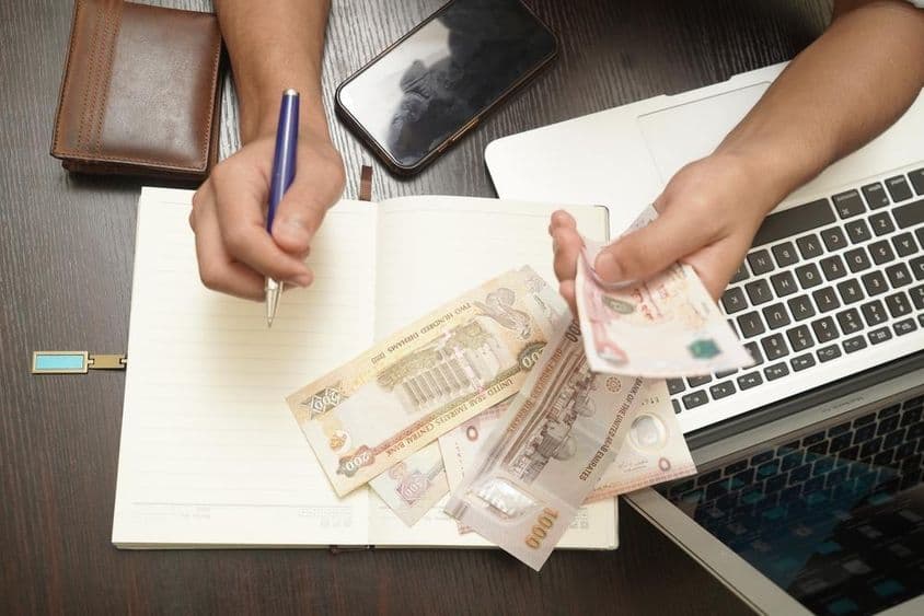 Muž počítajúci zväzok bankoviek Dirham Spojených arabských emirátov.