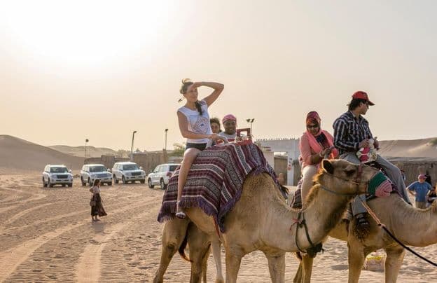 Turisti jazdiaci na ťavách v dubajskej púšti