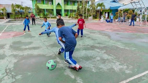 žáci na základnej škole hrajúci futbal