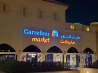 Osvetlené logo Carrefour market s arabským názvom značky