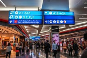 Cestujúci kráčajúci k odletovým bránam na medzinárodnom letisku v Dubaji
