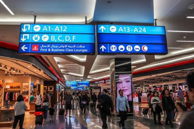 Cestujúci kráčajúci k odletovým bránam na medzinárodnom letisku v Dubaji